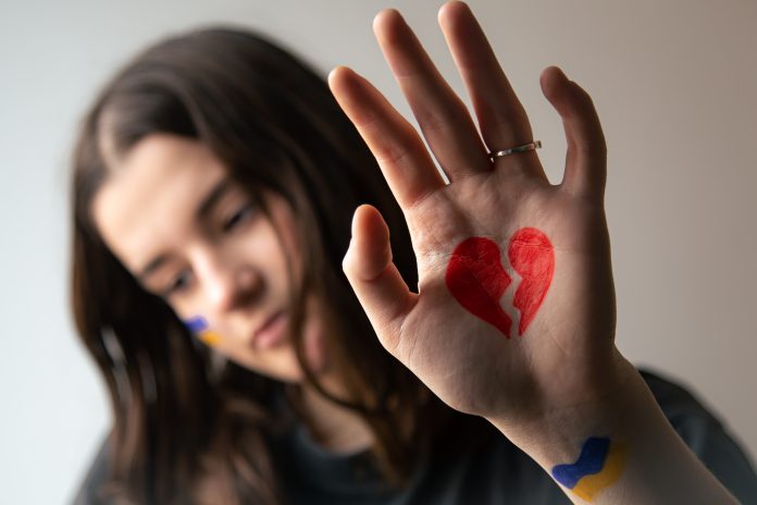 Ukrainian girl with a broken heart drawn on her hand, pain for Ukraine.