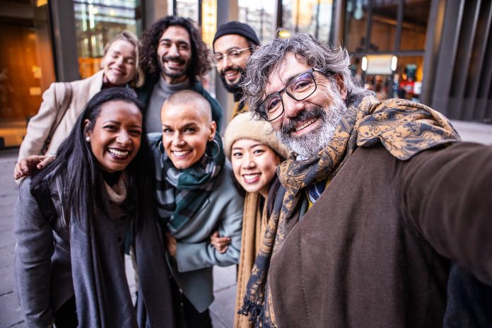 Happy coworkers taking a selfie together outdoors.