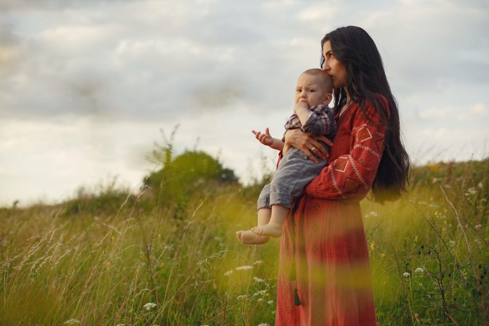 Mother with little son playing in a summer field