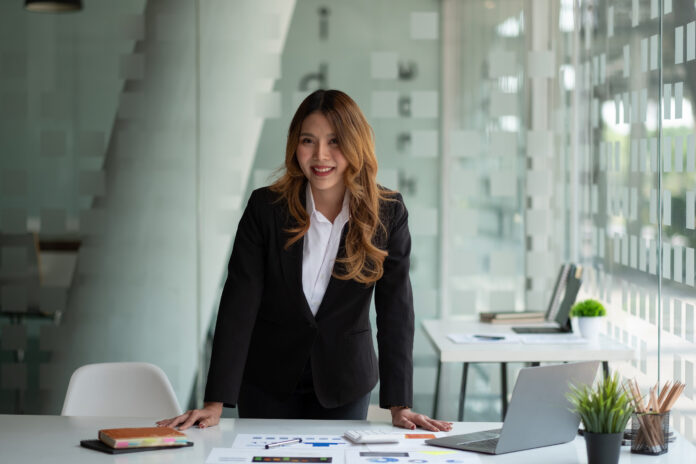 Portrait of attractive Asian Businesswoman working on laptop for marketing plan with paperwork