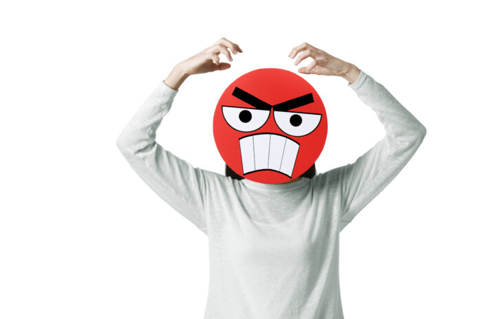 Young Chinese woman with a angry emoticon face in front of her face